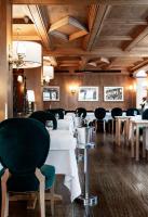 a dining room with white tables and green chairs at Hotel Tyrol in Selva di Val Gardena