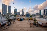 Una terraza en la azotea con sillas y sofás y un horizonte de la ciudad. en Domus Metro Hotel, en Tel Aviv
