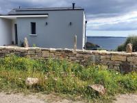 a stone wall in front of a house and a building at Reflets de la Mer... in Plomodiern
