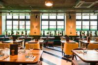 a restaurant with wooden tables and yellow chairs and windows at The Chamberlain in London
