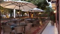 an outdoor patio with tables and chairs and umbrellas at Hotel das Palmeiras in Paracatu