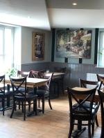 a restaurant with wooden tables and chairs and a painting on the wall at Al Forno Restaurant & Inn in Norwich