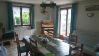 a dining room with a table and chairs and windows at le gutty - maison de vacances in Natzwiller