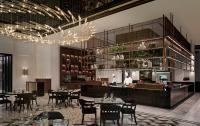 a restaurant with tables and a chef in a kitchen at Sofitel Dubai The Obelisk in Dubai