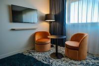 a hotel room with two chairs and a table and a tv at Live Hotels Bordeaux Lac in Bordeaux