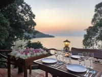 a wooden table with wine glasses and a view of the water at Banyan Bay Villas in Ko Jum