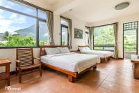 two beds in a room with large windows at Qian B&amp;B (Taroko) in Jiamin