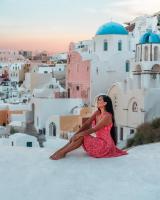 a woman in a red dress sitting on top of a building at Aspaki by Art Maisons in Oia