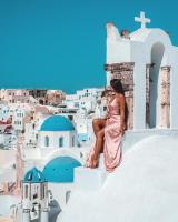 a woman in a pink dress sitting on the ledge of a building at Aspaki by Art Maisons in Oia