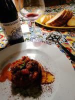 a plate of food on a table with a glass of wine at Kapuhala Sicily in Marzamemi