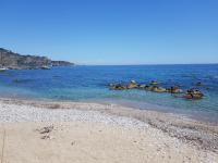 una playa con algunas rocas en el agua en Appartamenti via Lombardo, en Giardini Naxos