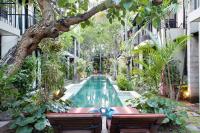 a swimming pool in the middle of a courtyard with trees at S&#39;cape Condotel in Sanur