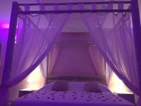 a bedroom with a bed with purple lighting at La Paillote Exotique Spa in Beaucaire