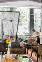 um homem parado num restaurante com mesas e cadeiras em Sofitel Mumbai BKC em Mumbai