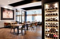 Un restaurante con mesas, sillas y botellas de vino. en Van der Valk Hotel Spa, en Spa