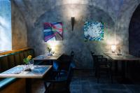 un restaurante con mesas, sillas y pinturas en las paredes en Oliva Hotel, en Veszprém