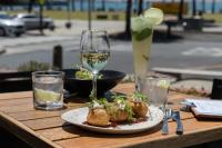 Una mesa con un plato de comida y una copa de vino. en Novotel Geelong, en Geelong