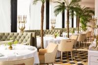um restaurante com mesas brancas e palmeiras em Victoria Jungfrau Grand Hotel & Spa em Interlaken