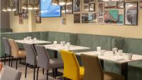 un restaurante con mesas y sillas blancas y un sofá verde en Holiday Inn Berlin Airport - Conference Centre by IHG, en Schönefeld