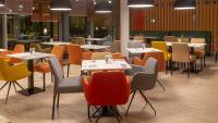 Un comedor con mesas y sillas y un escritorio. en Holiday Inn Berlin Airport - Conference Centre by IHG, en Schönefeld
