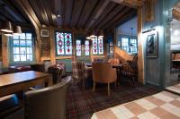 a restaurant with tables and chairs and stained glass windows at The Ostrich Inn Colnbrook London Heathrow in Slough