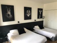 two beds in a room with pictures of animals on the wall at Logis Hôtel l&#39;Abricotine in Tain-lʼHermitage