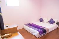 a bedroom with a bed with purple and white pillows at Golden Ocean Azure Hotel in Kenting
