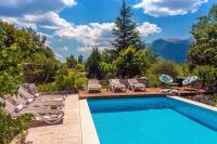 a swimming pool with chairs and a patio with mountains at Villa Tajina Kuca in Žeževica