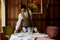 Een man zet een tafel in een restaurant. bij The Montagu Arms in Beaulieu