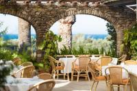 a restaurant with tables and chairs and a stone wall at Hotel Punta Sur in Tarifa