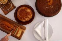 a table with cakes and plates and a person holding a knife at Hotel Punta Sur in Tarifa