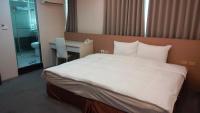 a bedroom with a large white bed and a desk at Shun-yi Business Hotel in Chiayi City