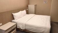 a bedroom with a large white bed and a table at Shun-yi Business Hotel in Chiayi City