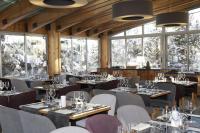 a dining room with tables and chairs and windows at Le Pic Blanc in L&#39;Alpe-d&#39;Huez