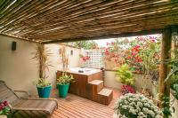 a wooden deck with a hot tub and some plants at Pousada Casa do Catavento in Búzios