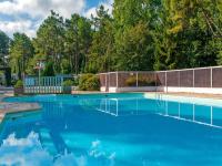 a swimming pool with blue water in a yard at LE ILÔ - camping la dune blanche in Camiers