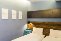 a bedroom with two beds and two paintings on the wall at 仁愛小公館-市區近東大門 in Hualien City