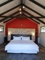 1 dormitorio con 1 cama blanca grande y pared roja en Khan River Lodge, en Wilhelmstal