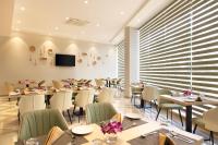 Un restaurante con mesas y sillas y un televisor de pantalla plana. en Click Hotel Bangalore - International Airport, en Devanhalli