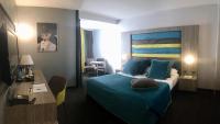 a hotel room with a bed with a blue bedspread at Hotel Palladia in Toulouse
