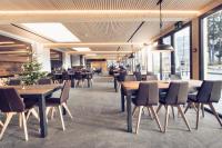 Un comedor con mesas y sillas de madera. en Frutigresort, en Frutigen