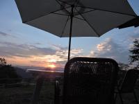 an umbrella and a chair with a sunset in the background at Eco-Cabañas Altozano Nimaima in Nimaima