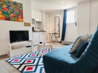 a living room with a blue couch and a kitchen at STUDIO COSY LE Ti PARIS WIFI &amp; NETFLIX in Deuil-la-Barre