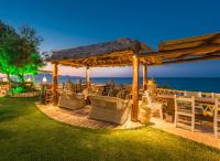 un gazebo in legno con sedie e un tavolo e l'oceano di Porta del mar Beach Resort a Méson Yerakaríon