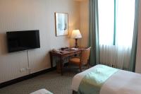 a hotel room with a desk and a bed and a television at Wei-Yat Grand Hotel in Anping