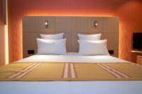 a large bed with white pillows in a room at Nash Airport Hotel in Geneva