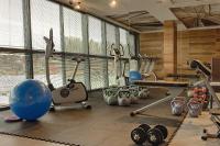 a gym with exercise equipment in a room with windows at Hotel Mikołajki Leisure &amp; SPA in Mikołajki