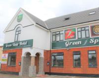 Un edificio blanco y rojo con un cartel verde. en Green View Hotel Near Dartford, en Dartford