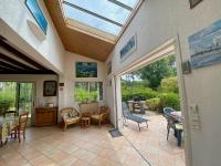a conservatory with a patio with a table and chairs at Cottage with a big idyllic garden at the lake in Lacanau