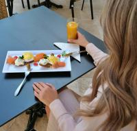 アラドにあるGrant Boutique Hotelの食べ物の皿を持ってテーブルに座っている女性